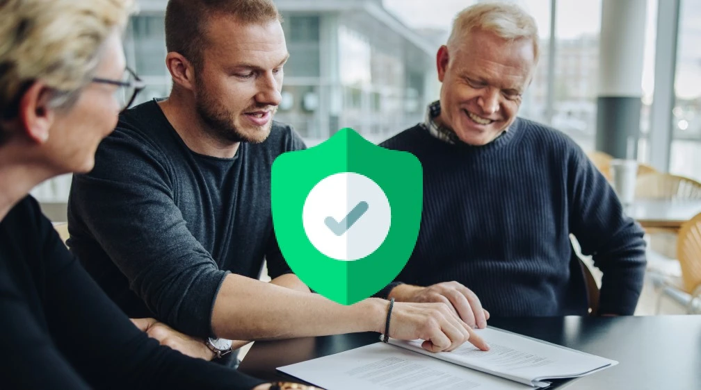 Eine Gruppe von Menschen sitzt an einem Tisch und schaut auf ein Blatt Papier