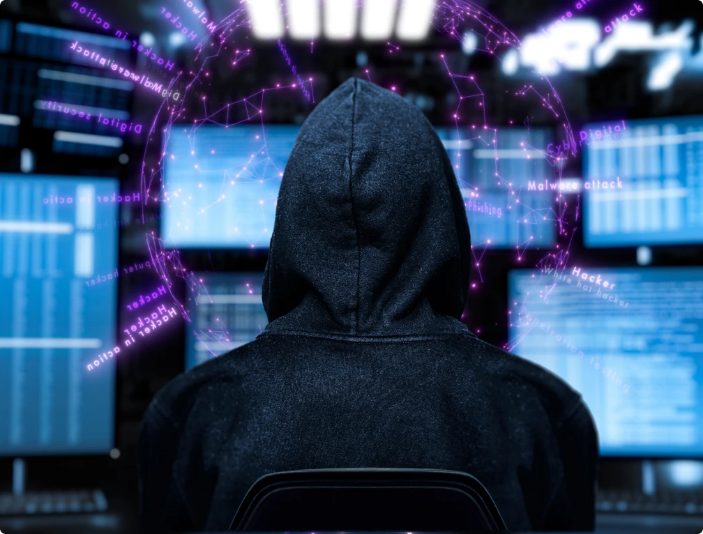 Ein Mann in einer Kapuze sitzt vor einem Computerbildschirm und sieht sich etwas an