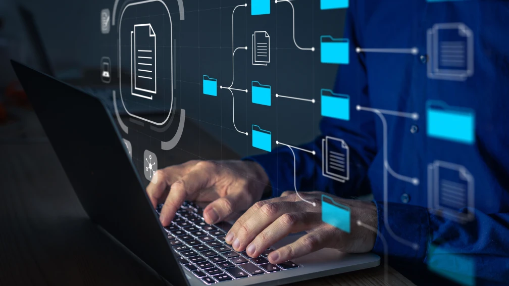 Ein Mann arbeitet an einem Laptop mit einem Diagramm dahinter