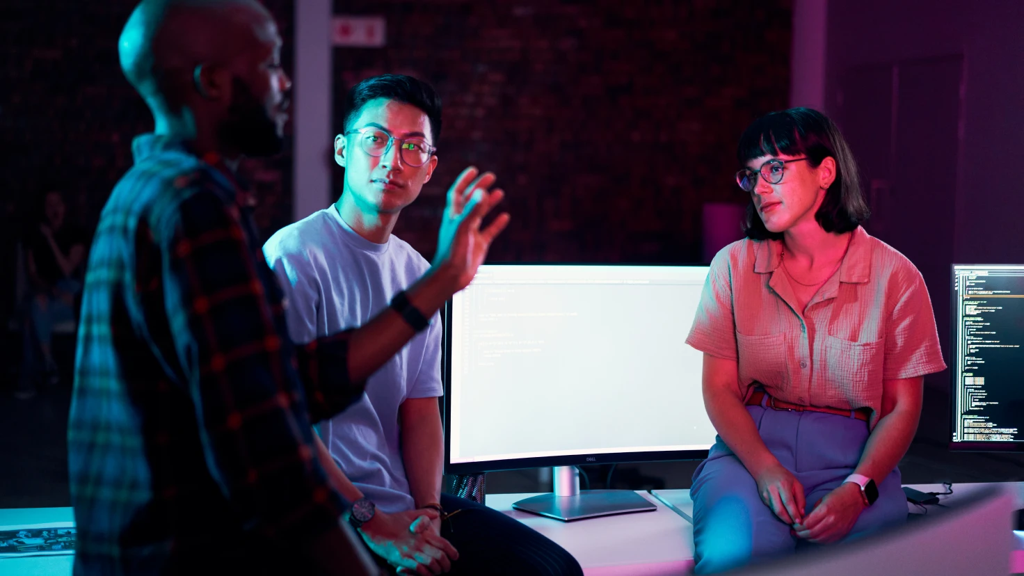 Eine Gruppe von Menschen sitzt um einen Tisch und spricht vor einem Computerbildschirm