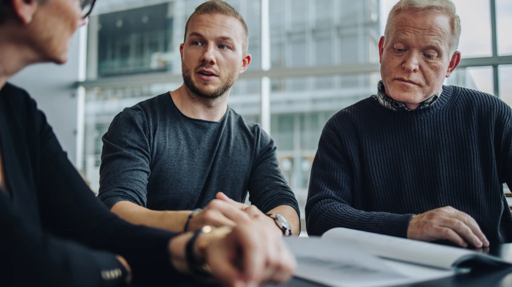 Eine Gruppe von Menschen sitzt an einem Tisch und schaut auf ein Buch
