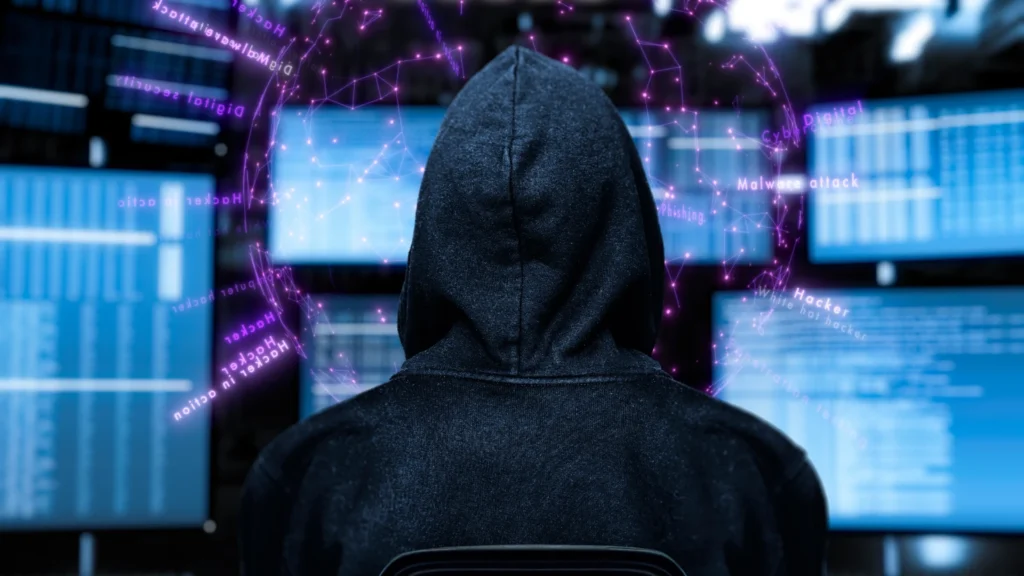 Ein Mann in einer Kapuze sitzt vor einem Computerbildschirm und sieht sich etwas an