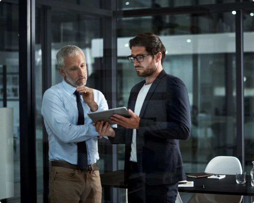 Zwei Männer stehen nebeneinander und schauen auf ein Tablet