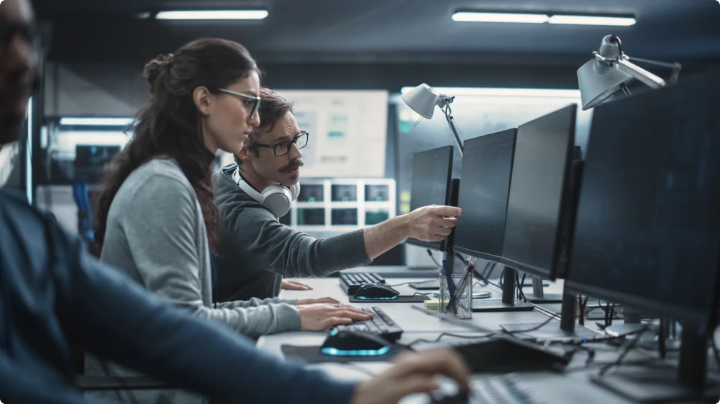 Eine Gruppe von Menschen sitzt an einem Schreibtisch und arbeitet an Computern