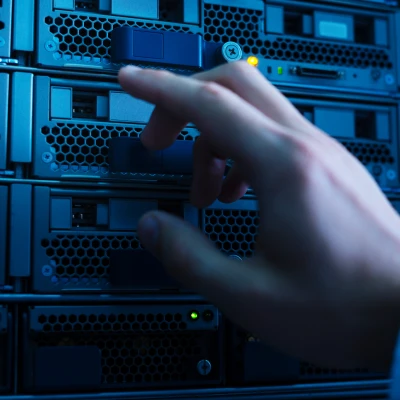Eine Hand greift nach einem blauen Gerät in einem Serverraum