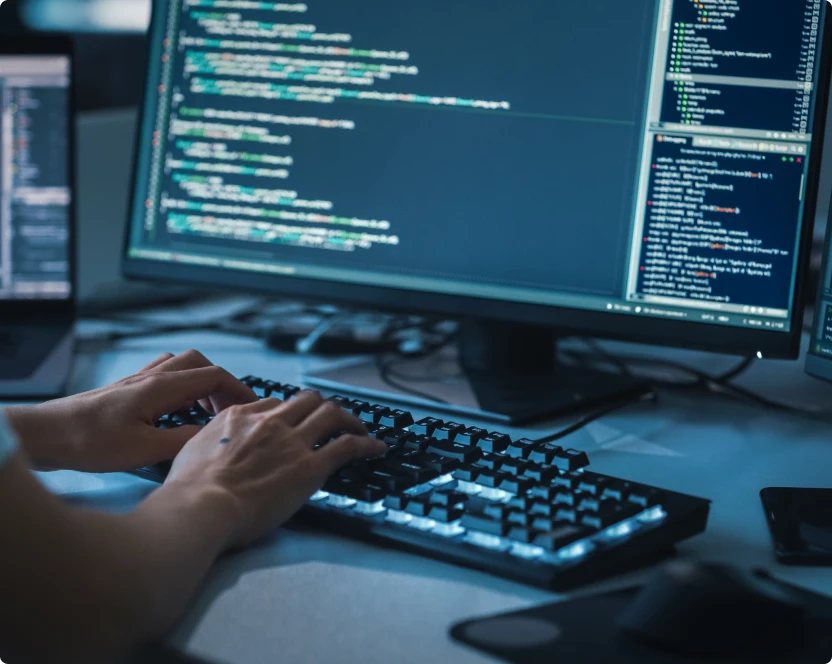 Eine Person tippt auf einer Tastatur vor einem Computerbildschirm