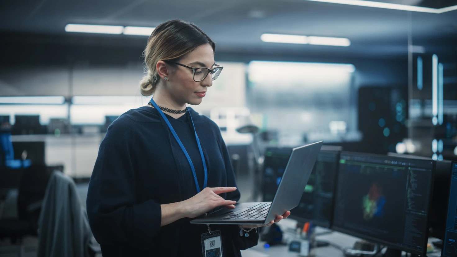 Eine Frau mit Brille hält einen Laptop in der Hand