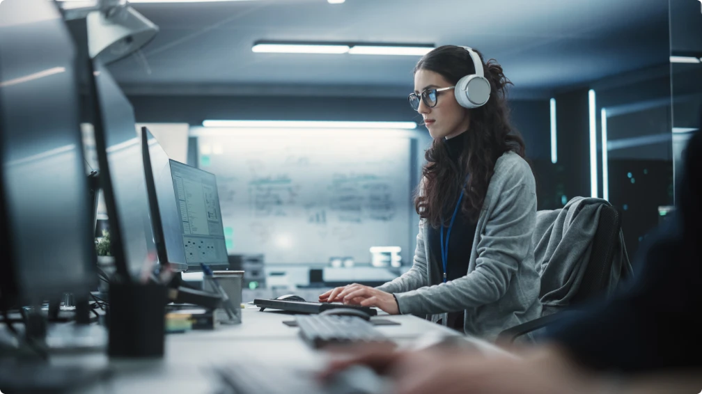 Eine Frau mit Kopfhörern arbeitet an einem Computer