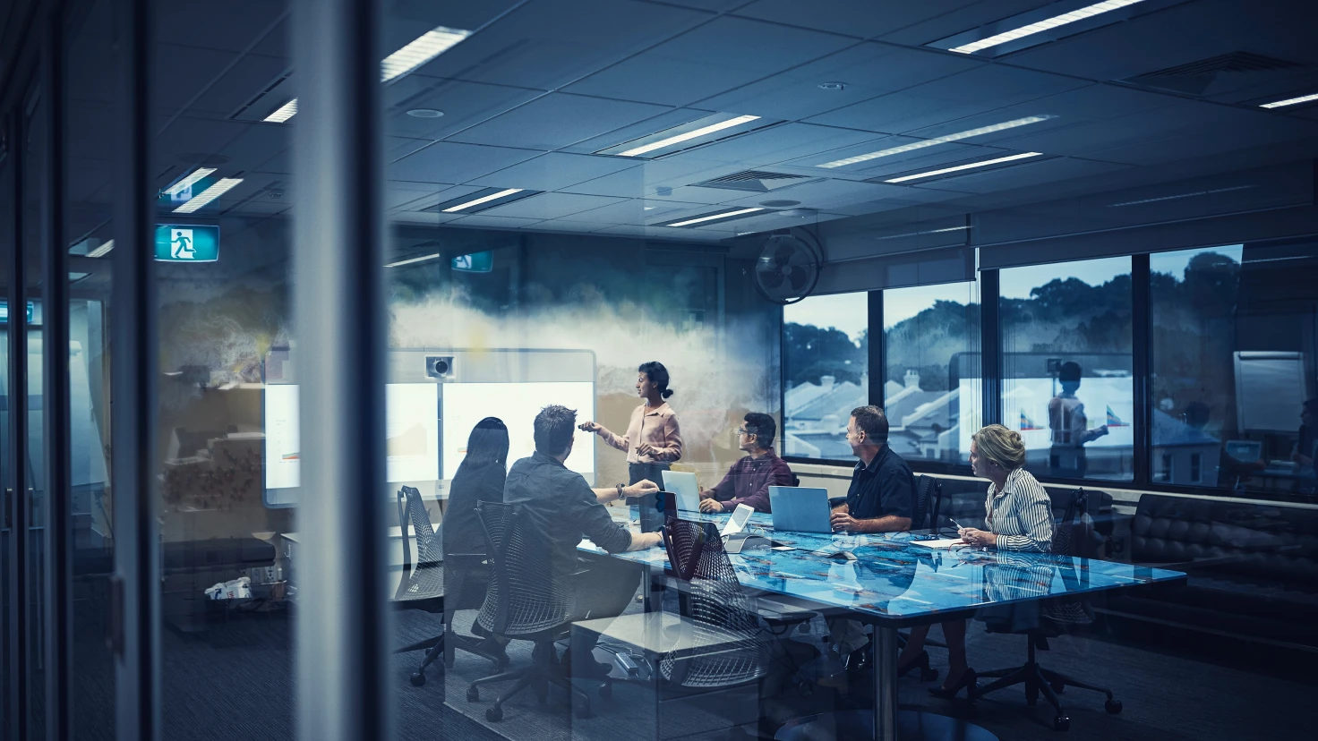 Eine Gruppe von Menschen sitzt um einen Tisch und arbeitet an Laptops