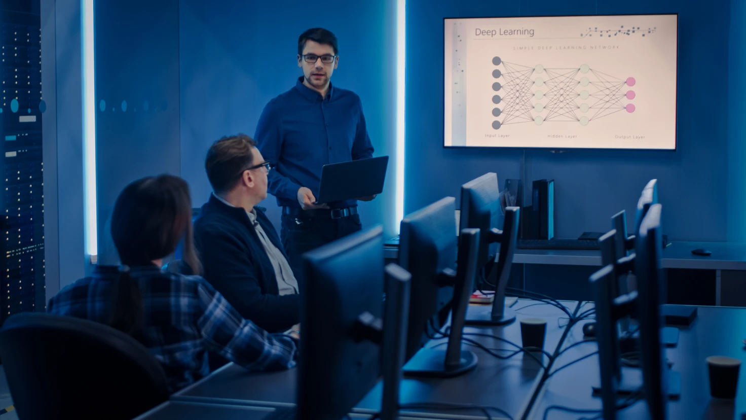 Eine Gruppe von Menschen steht um einen Tisch und schaut auf ein Tablet